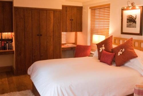 a bedroom with a large white bed with red pillows at Swan House in Beccles
