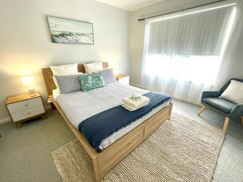 a bedroom with a bed with a chair and a window at The Whitehouse in Emu Bay