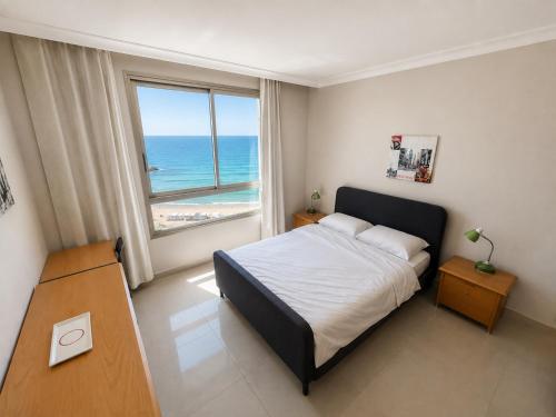 a bedroom with a bed and a view of the ocean at Azure apartments Haifa in Haifa