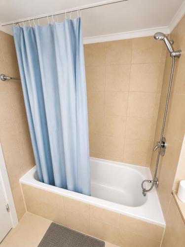 a shower with a blue shower curtain in a bathroom at Azure apartments Haifa in Haifa