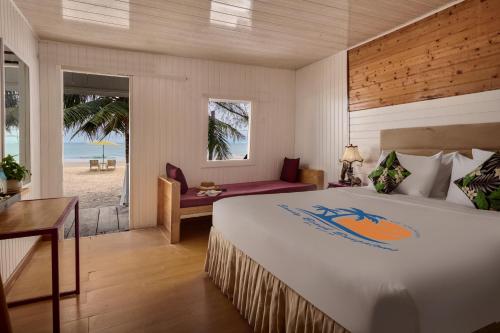 a hotel room with a bed and a desk and a window at Sandy Beach Bungalows by EHM in Koh Rong Sanloem