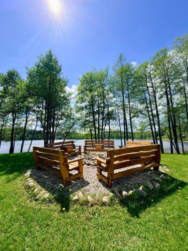 a row of wooden benches sitting in a park at Lake Lodge Labanoras in Šnioriškės