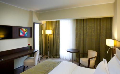 a hotel room with a bed and a desk and a window at Hotel Pietroasa in Buzau