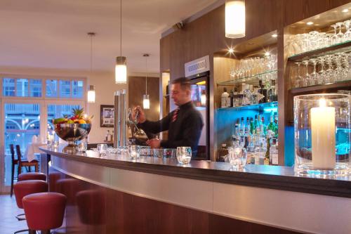a man bartender behind the bar in a restaurant at Hotel Villa Belvedere in Binz