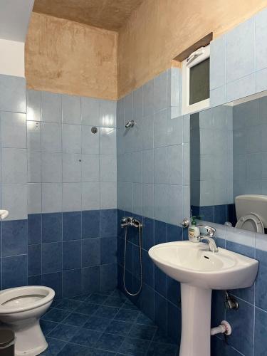 ein blau gefliestes Badezimmer mit Waschbecken und Toilette in der Unterkunft Sunset Dream Guesthouse in Himarë