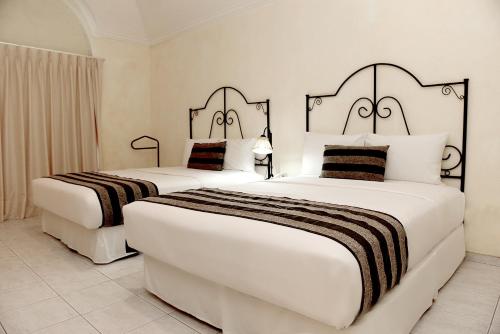two beds in a hotel room with white at Buganvillas Hotel Suites in Santa Cruz de la Sierra