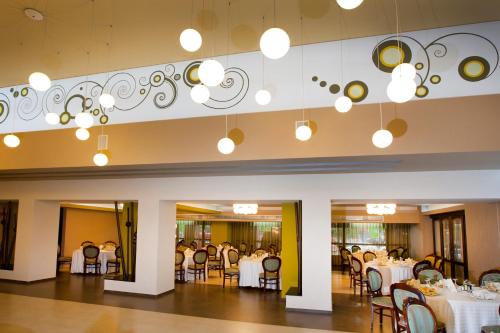 une salle à manger avec des tables et des chaises blanches dans l'établissement Hotel Pietroasa, à Buzău