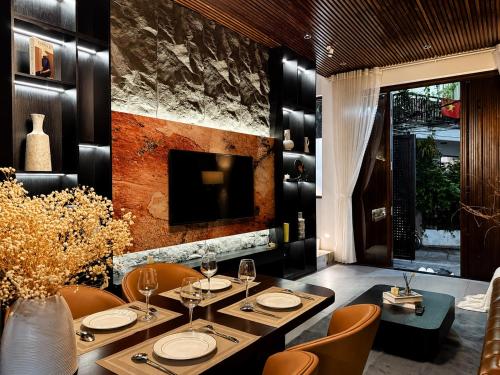 a dining room with a table and chairs and a television at MONO HAUS Villa Danang in Danang