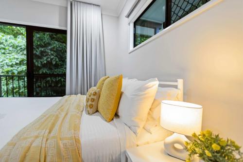 a bedroom with a bed with a lamp and a window at Rainforest Escape with Pool & Mountain Views in Caravonica