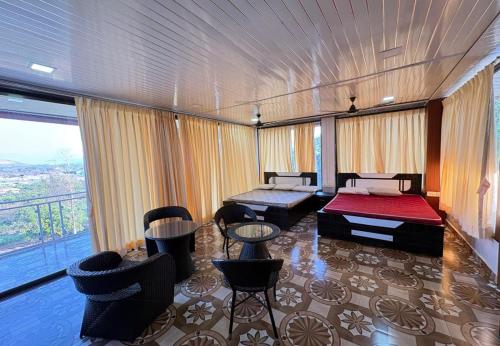 a room with a bed and chairs and a large window at Attra Farms in Karjat