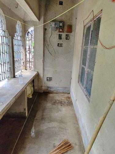 an empty room with windows in an old building at Pranusree Holiday Home in kolkata