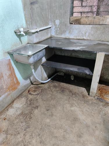a dirty bathroom with a sink and a bench at Pranusree Holiday Home in kolkata
