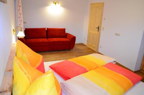 a room with a bed with colorful pillows and a couch at Kleintödlinggut in Leogang