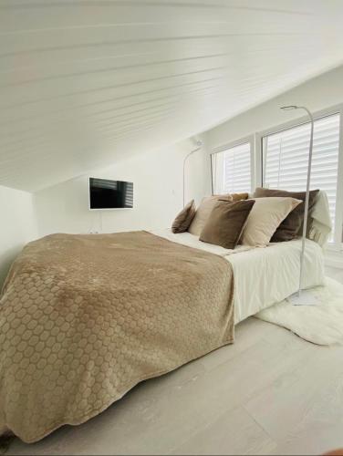 a white bedroom with a large bed and a television at Little White House in Anglet