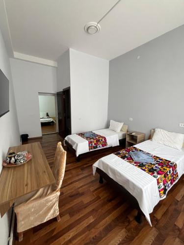 a room with two beds and a table and a table and chairs at Ichan Kala Silk Road Guest House in Khiva