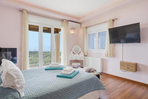 a bedroom with a bed with a tv on the wall at Villa Sarakinos in Kriniás