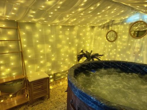 a large tub in a room with lights on the wall at Les Clos De La Vigne in Vals-les-Bains