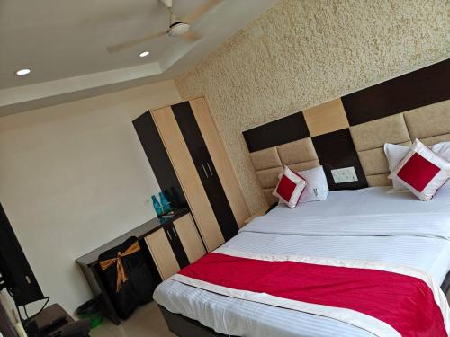 a bedroom with a large bed with red and white pillows at Hotel Travora Suits -Lalquila in Bhubaneshwar