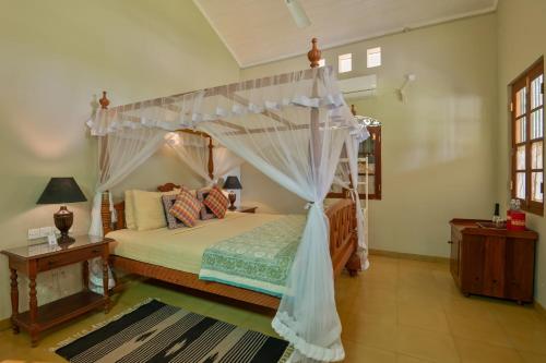 a bedroom with a bed with a canopy at Villa Sethawadi Hotel and Kitesurf Centre in Kalpitiya