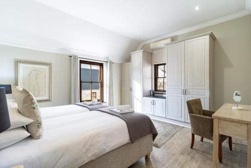 a bedroom with a large white bed and a desk at Winelands Golf Lodges 10 in Stellenbosch