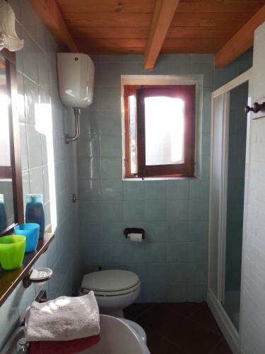 a bathroom with a toilet and a window at Space in Paradise in Castelbuono