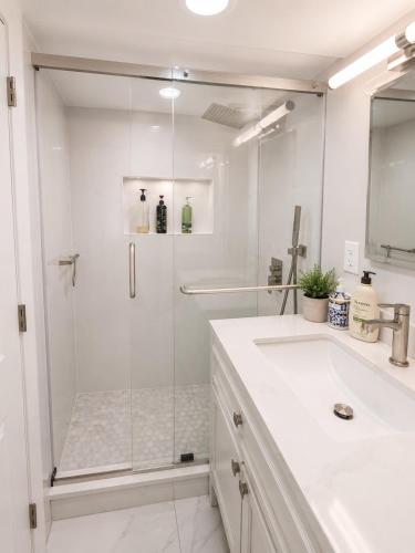 a white bathroom with a shower and a sink at Parkside luxury suite and EV station in Jenkintown
