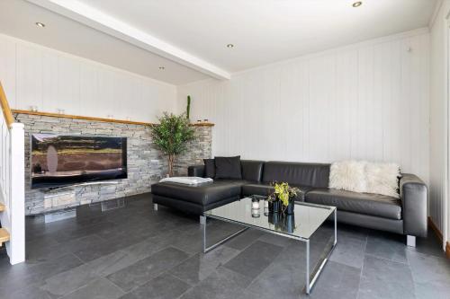 a living room with a black couch and a fireplace at Beach House With Multiple Terraces In Holmsbu in Holmsbu