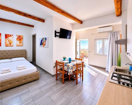 a bedroom with a bed and a table and a kitchen at Sole E Mare in Marina di Fuscaldo