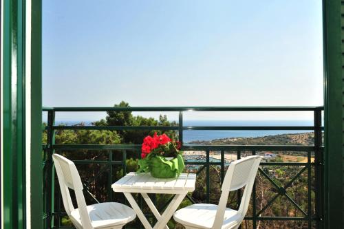 two chairs and a table with flowers on a balcony at Mykali Hotel in Pythagoreio