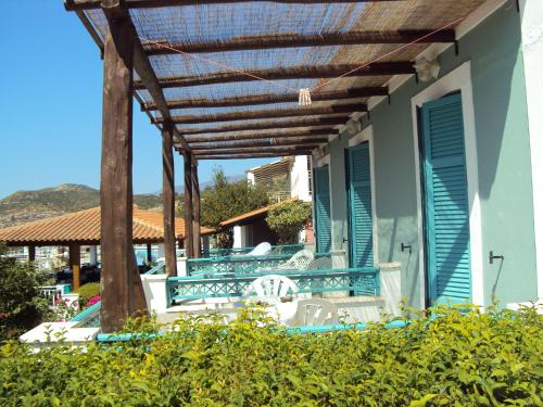 a patio with a pergola and chairs on a house at Mykali Hotel in Pythagoreio