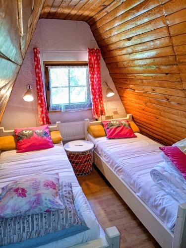 two beds in a room with wooden walls at Willa 7 in Korbielów