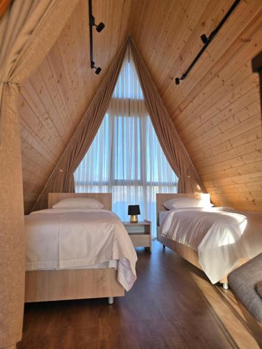 two beds in a room with a large window at V Peaks Family A Frames in Dilijan in Dilijan