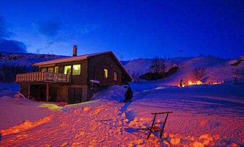 a log cabin in the snow at night at Rivdnji Holiday Home Smørfjord in Russenes