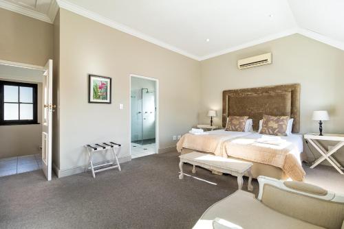 a bedroom with a large bed and two chairs at Winelands Golf Lodges 15 in Stellenbosch
