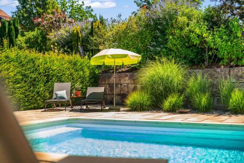 a swimming pool with an umbrella and two chairs and a table at Weingut Landerer in Vogtsburg