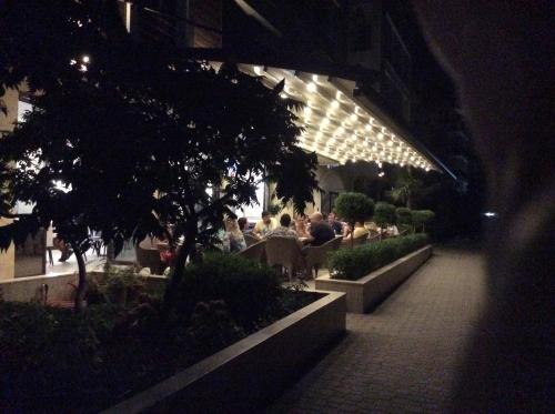 a building with people sitting at tables in a courtyard at night at APART-HOTEL Stamopolu Lux с изглед към морето in Primorsko