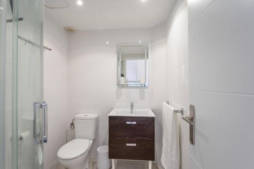 a white bathroom with a toilet and a sink at Villa Noa in Cala en Bosc