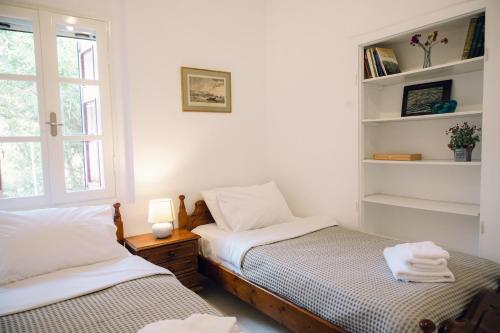 two beds in a room with white walls and windows at Emporios 1930, Seafront stone house in Emporeiós