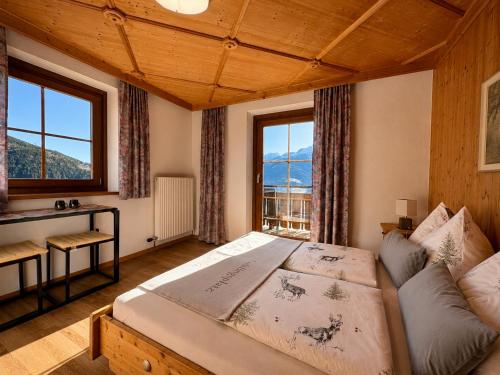 a bedroom with a bed and a desk and windows at Hochleiten-Gut in Niedernsill