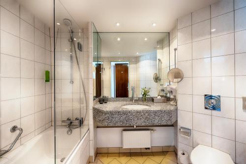 a bathroom with a tub and a sink and a shower at Welcome Parkhotel Bochum in Bochum