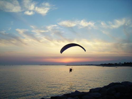 a person flying a kite in the water at sunset at Hotel Marea in Grado
