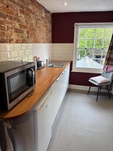 a kitchen with a microwave on top of a counter at The Flat The Plough in Birdbrook