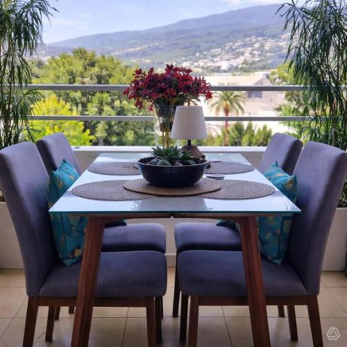 a table with chairs and a table with flowers on a balcony at le Cosy - Studio Apparthotel in Saint-Denis
