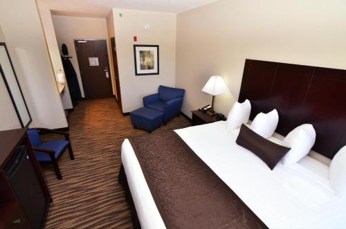 a hotel room with a bed and a blue chair at Cobblestone Inn & Suites - Manning in Manning