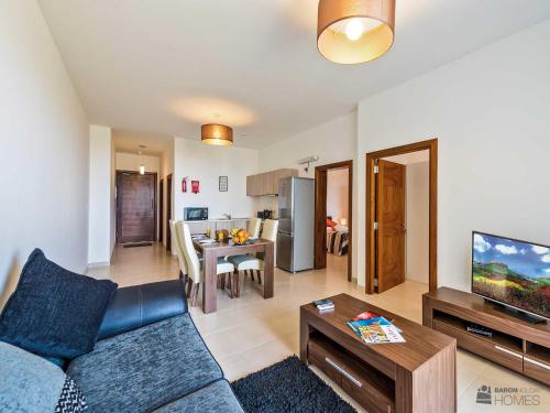 a living room with a blue couch and a television at Hillock Residence Apartments in Marsalforn