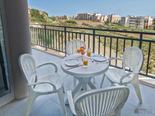 a white table and four chairs on a balcony at Hillock Residence Apartments in Marsalforn