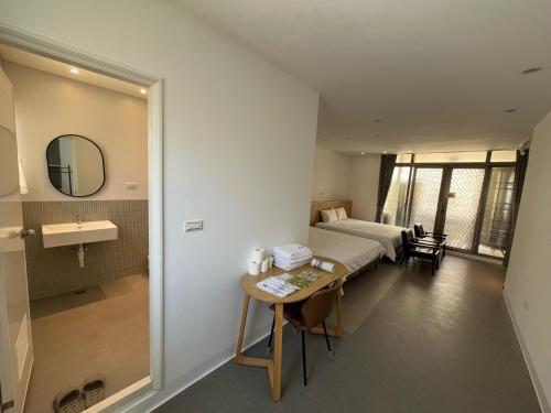a hotel room with a bed and a desk and a sink at Rolling Pin Homestay in Tainan
