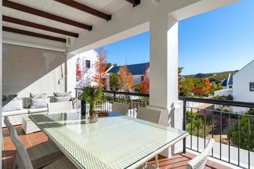 a patio with a glass table and chairs on a balcony at Winelands Golf Lodges 24 in Stellenbosch
