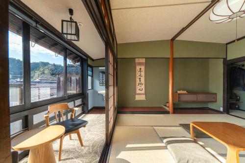 a living room with a table and chairs and windows at 湯宿ささくら in Kinosaki