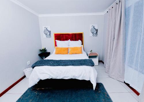 a bedroom with a large bed with orange pillows at Goshen villas in Mbabane